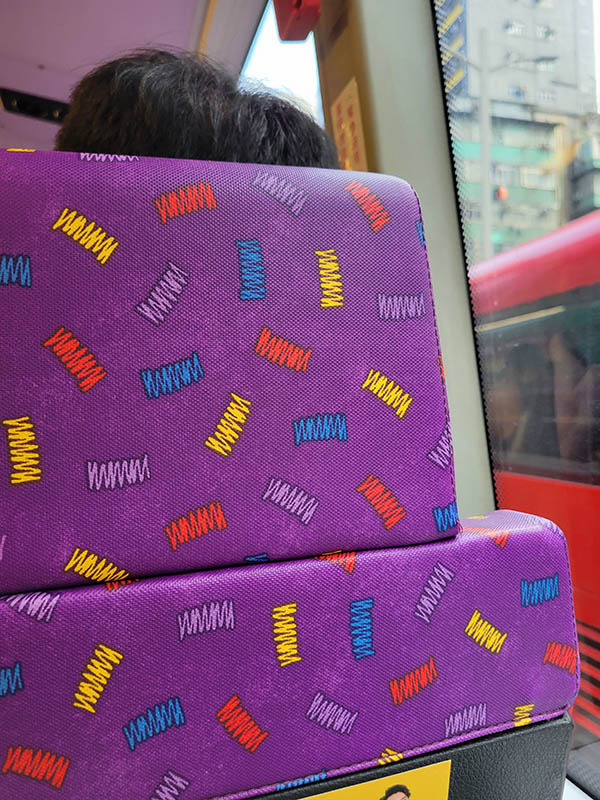 Purple seats on a bus with different color bars